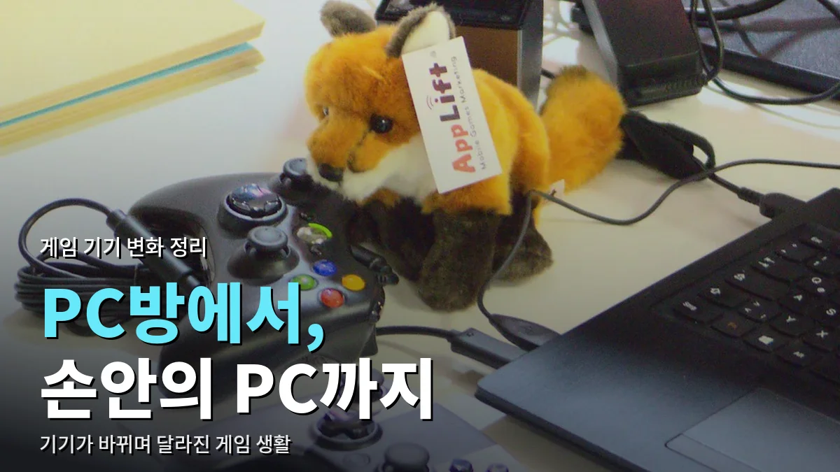 책상 위 노트북 옆에 놓인 게임 컨트롤러 두 개